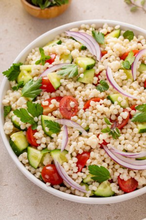 Photo for Pearl couscous salad with fresh vegetables and herbs in a serving bowl, healthy side dish idea - Royalty Free Image