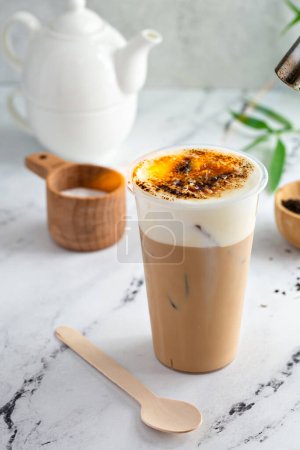 Creme brulee milk tea with cold foam and caramelized sugar on top being torched with a culinary torch