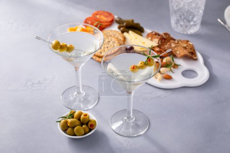 Foto de Cóctel tradicional de martini con guarnición de aceitunas y tabla de charcutería - Imagen libre de derechos