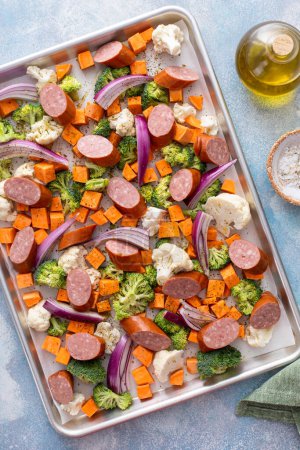 Sheet pan dinner with sausage and vegetables ready to be roasted with broccoli and cauliflower