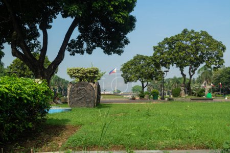 Photo for Rizal Park, Manila, Philippines July 2, 2014: The Philippine Flag framed by grasses and trees at the Rizal Park in Manila, Philippines - Royalty Free Image