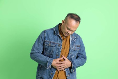 Photo for The 40s adult Asian man with jean shirt standing on the green background. - Royalty Free Image