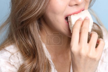 Téléchargez les photos : La femme asiatique manger des sandwichs sur fond bleu. - en image libre de droit