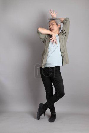 The 40s Asian man with smart casual clothes standing on the grey background. 