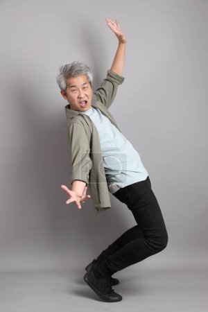 The 40s Asian man with smart casual clothes standing on the grey background. 