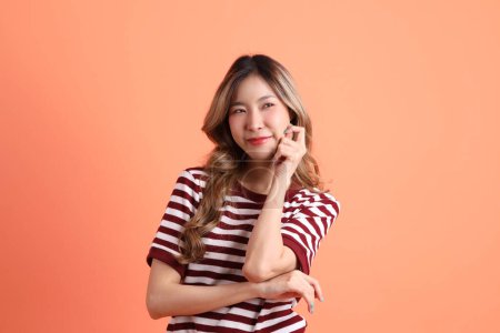 Foto de La joven mujer asiática en ropa casual con gesto de pensar en el fondo naranja - Imagen libre de derechos