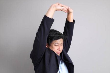 The Asian Businessman with formal dressed with gesture of exhausted on the gray background.