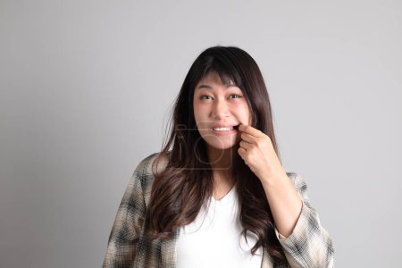 Téléchargez les photos : La femme asiatique adulte debout sur le fond gris, avec un geste stupide et drôle. - en image libre de droit