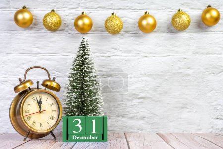 Foto de Árbol de Navidad decorativo, calendario perpetuo verde y reloj despertador de bronce sobre fondo blanco con ajo festivo. Concepto de Año Nuevo. Banner, encabezado, fondo con espacio de copia - Imagen libre de derechos