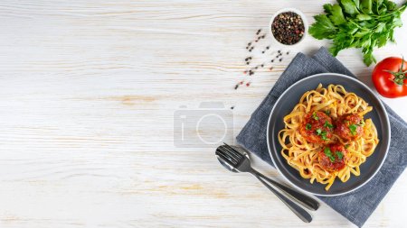 Téléchargez les photos : Homemade spaghetti with tomato sauce meatballs and spices served on white background. Tasty cooked pasta and meat balls made with minced beef, food ingredients. Top View, Flat lay, banner, copy space - en image libre de droit