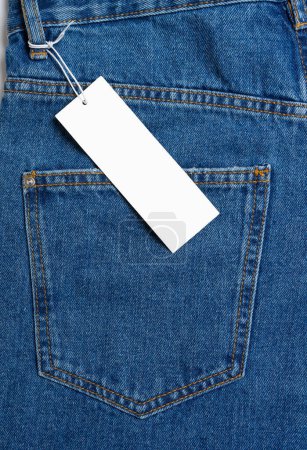 Foto de Back side pocket and price tag of blue jeans pants close-up. Denim background, texture, mockup. Fashion concept, business, shopping, sale. Design detail, button and seams, clothing tag, copy space - Imagen libre de derechos