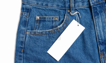 Foto de Front side pocket and price tag of blue jeans pants close-up isolated on white background, mockup. Fashion concept, business, shopping, sale. Design detail, button and seams, clothing tag, copy space - Imagen libre de derechos