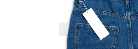 Foto de Back side pocket and price tag of blue jeans pants close-up isolated on white background, mockup, banner. Fashion, business, shopping, sale. Design detail, button and seams, clothing tag, copy space - Imagen libre de derechos