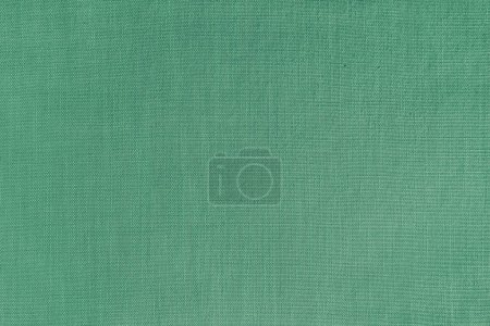 Texture background of green linen fabric. Textile structure, cloth surface, weaving of natural cotton fabric closeup, backdrop, wallpaper.