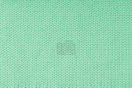 Close up background of knitted wool fabric made of viscose yarn, green color wool knitwear texture. Sweater, pullover knitted jersey background. Fabric abstract backdrop, wallpaper
