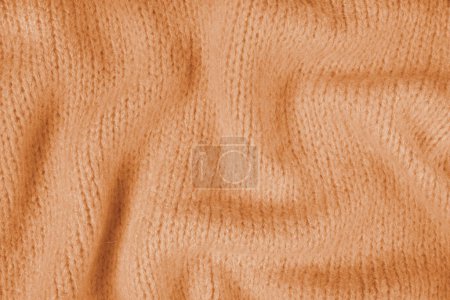 Primer plano de tela de punto naranja hecha de hilo de viscosa. Lana de punto arrugada, fondo de textura de punto suave. Fondo de jersey arrugado de punto abstracto, fondo de pantalla.