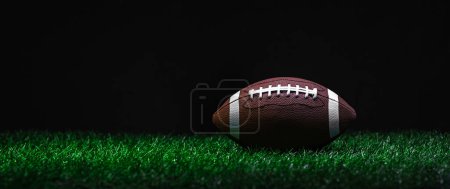 Téléchargez les photos : Football américain sur herbe verte, sur fond noir. Affiche thématique sport horizontal, cartes de vœux, en-têtes, site web et ap - en image libre de droit