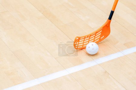 Photo for Floorball stick and white ball on hardwood court floor. Horizontal sport theme poster, greeting cards, headers, website and app - Royalty Free Image