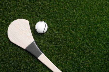 Photo for Hurling bat and sloitar on green grass. Horizontal sport theme poster, greeting cards, headers, website and app - Royalty Free Image