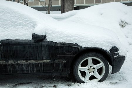 Photo for Dirty black car side view, covered with snow passenger transport on a cold winter day on a city street, nobody. - Royalty Free Image