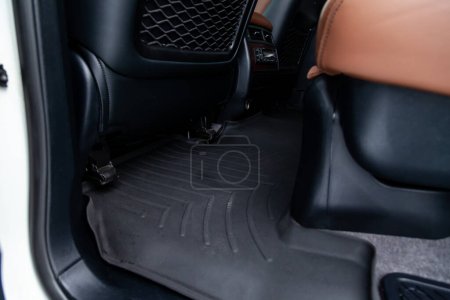 Alfombras limpias de caucho negro debajo del asiento trasero del pasajero en el taller para la limpieza en seco del vehículo. Industria de servicios automotrices. Interior del sedán
.
