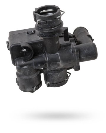 Heating system valve made of black plastic on a white isolated background in a photo studio. A unit of a liquid cooling system. Used spare parts from junkyard catalog.