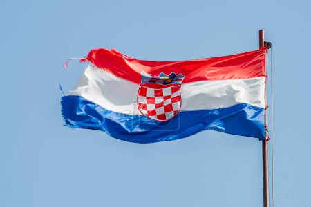 Red white and blue flag with coats of army of Croatia waving in the wind