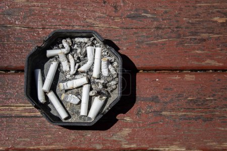 Foto de Ashtray full of cigarette butts on brown wooden table, top view - Imagen libre de derechos