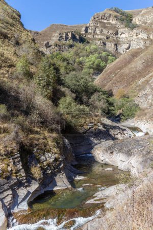 Téléchargez les photos : Belle petite cascade de montagne avec des eaux rapides et des rochers au Daghestan, dans le Caucase du Nord, en Russie. Voyage saisonnier naturel fond extérieur avec protection solaire - en image libre de droit