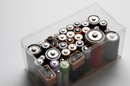 Foto de Baterías coloreadas usadas en un recipiente de plástico sobre fondo blanco. - Imagen libre de derechos