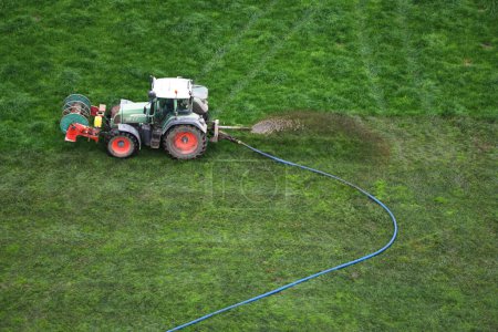 Téléchargez les photos : Les champs d'herbe des eaux de fermier utilisant des machines dans une vue aérienne, favorisant une croissance saine. - en image libre de droit