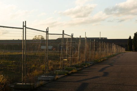 Téléchargez les photos : Des clôtures de sécurité marquent la frontière entre l'asphalte et les prairies, créant une séparation claire entre les deux zones. - en image libre de droit