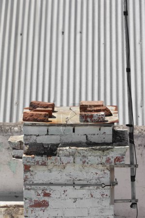 Téléchargez les photos : Au-dessus du toit, la vieille cheminée est fermée, avec son conduit scellé à l'aide de briques. - en image libre de droit