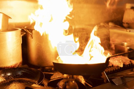 Photo for Chef cooking with a flaming pan, displaying their culinary skills. - Royalty Free Image