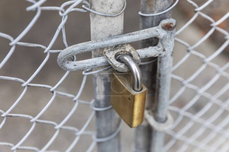 Téléchargez les photos : Cadenas rouillé est attaché à une clôture métallique. - en image libre de droit