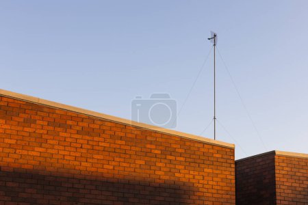 Téléchargez les photos : Grande antenne sur le mur de briques sur fond de ciel bleu clair. - en image libre de droit