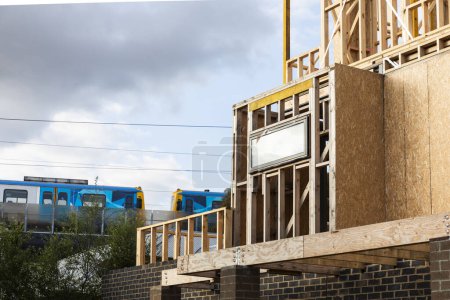 Téléchargez les photos : Maison résidentielle en construction avec un train qui passe à proximité. - en image libre de droit