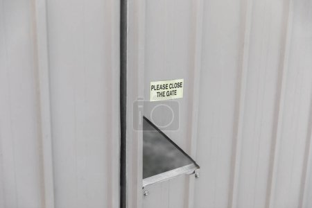 Foto de Cartel pegado a una puerta de metal que recuerda a la gente cerrar la puerta. - Imagen libre de derechos