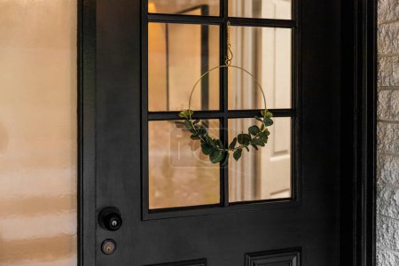 Téléchargez les photos : Vue rapprochée d'une porte noire dotée d'une couronne décorative minimaliste. - en image libre de droit