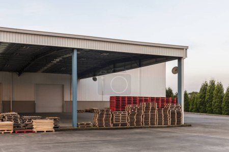 Wooden pallets stacked in rows outside a warehouse building.