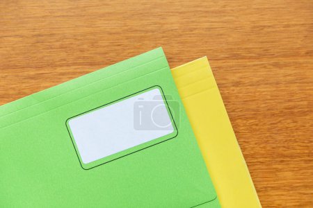 Téléchargez les photos : Dossiers manila jaune et vert empilés sur une table en bois. - en image libre de droit