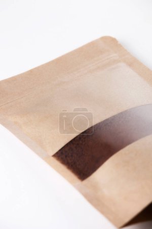 Téléchargez les photos : Sac en papier kraft marron rempli de café moulu sur fond blanc. - en image libre de droit