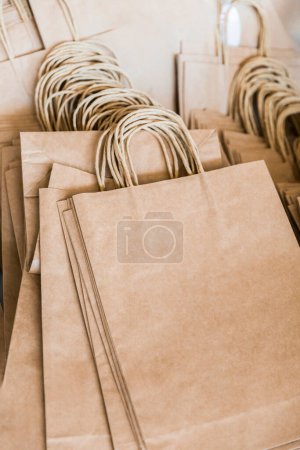 Téléchargez les photos : Emballages de papier artisanal empilés avec poignées torsadées, prêts à être utilisés pour l'emballage ou le transport d'articles. - en image libre de droit