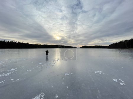 Photo for Kid ice skating on natural lake ice during a overcast afternoon. Sweden - Royalty Free Image