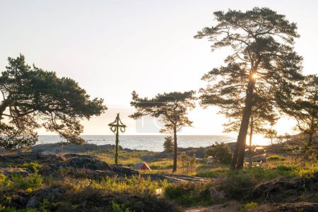 Photo for Sunrise of a classic midsommer pole with small tents with campers at the coast line of Roslagen. Sweden - Royalty Free Image