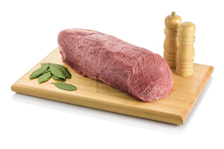 Raw eye round, a beef steak from the rear leg of the cow, ready to be cooked. On a cutting board with bay leaves and salt and pepper grinders aside. Isolated on white background.