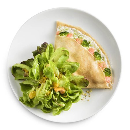 Téléchargez les photos : Crêpe avec mayonnaise, saumon et brocoli, avec salade de côté. Sur une plaque blanche sur un backgroud blanc. - en image libre de droit