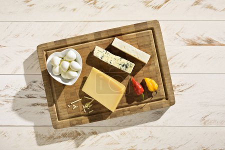 Téléchargez les photos : Assortiment de délicieux fromages en planche à découper sur une table en bois blanc. Apéritif parfait pour servir. - en image libre de droit