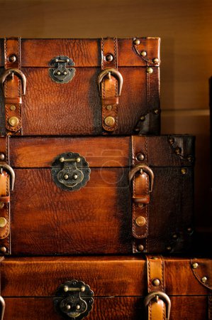 Three vintage leather chests of different sizes stacked on top of each other