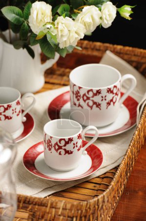 Foto de Kit de copas de cerámica de patrón arabesco rojo en una bandeja de mimbre - Imagen libre de derechos